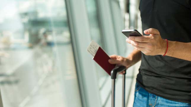 man in airport holding boarding pass and smartphone