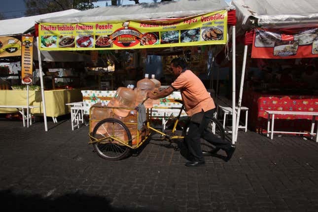 A vendor pushes his bicycle cart filled with 18-liter jugs of bottled water to sell to owners of street food stalls in Mexico City. Tap water is unreliable and often contaminated, so most Mexico City residents have to buy drinking water instead.