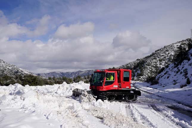 A worker plows snow along State Route 138 near Hesperia, California on Wednesday, March 1, 2023.