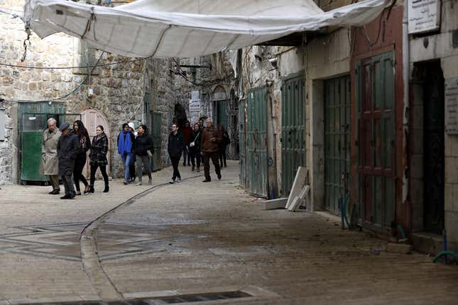 People walk down an empty street during a full strike in Hebron, West Bank.