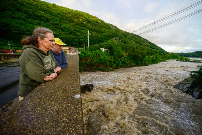 People stand on the Vilas Bridge, in Bellows Falls, Rockingham, Vt., to watch the water from the Connecticut River flow through on Monday, July 10, 2023. 