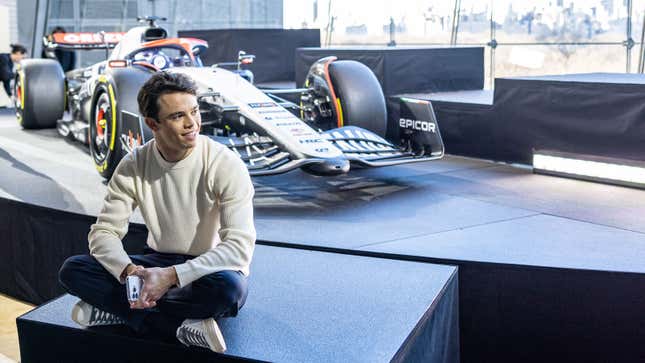 A photo of Nyck de Vries sat in front of the 2023 AlphaTauri F1 car. 