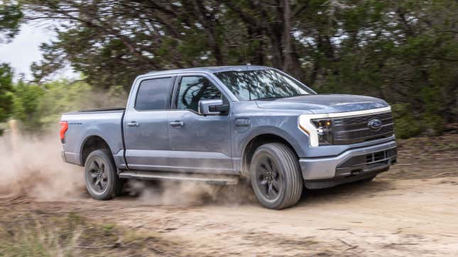 A photo of a blue Ford F-150 Lightning truck driving through the dust. 