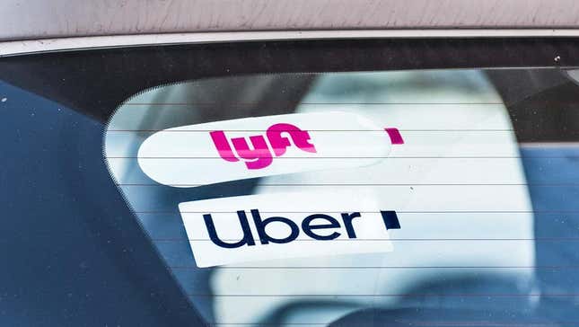 Uber and Lyft stickers in the window of a car. 