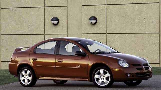 Brown Dodge Neon parked in front of a white stone building.