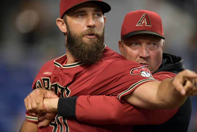 Madison Bumgarner is restrained by a coach.