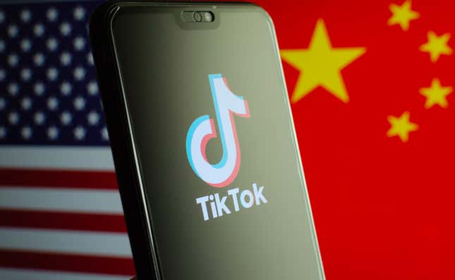 A phone with the TikTok logo in front of American and Chinese flags.