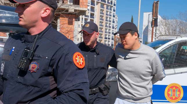 Montenegrin police officers escort an individual who is believed to be one of the most wanted fugitives, South Korean citizen, Terraform Labs founder Do Kwon in Montenegro's capital Podgorica, Friday, March 24, 2023.