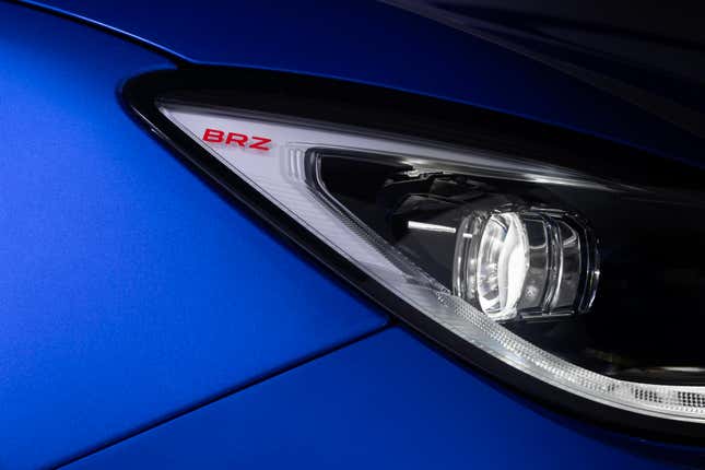 Close-up teaser image of the side of a Subaru BRZ headlight with the model name inscribed in red on the plastic.