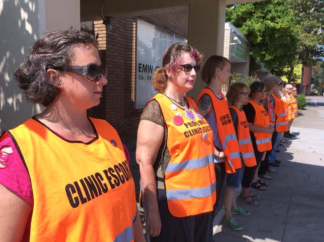 FILE - In this July 17, 2017 file photo, escort volunteers line up outside the EMW Women's Surgical Center in Louisville, Ky., the state's only abortion clinic. Anti-abortion groups are challenging a new Louisville law that creates a buffer zone around medical centers. It bars protesters from an area in front of a downtown abortion clinic. The new law passed by the Louisville Metro Council last May 2021 creates a 10-foot-wide zone outside healthcare facilities, including the EMW Women’s clinic. (AP Photo/Dylan Lovan, File)