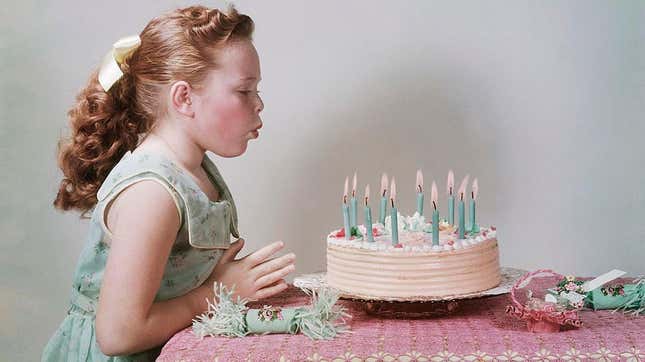 Colorized vintage photo of young girl blowing out candles on birthday cak