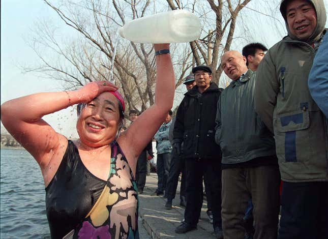 Xiao Rung, 66, of Beijing rinses off with bottled tap water after celebrating International Women’s Day with a winter swim in a central Beijing lake on March 8. She joined several other women residents. The water temperature was 2 °C.