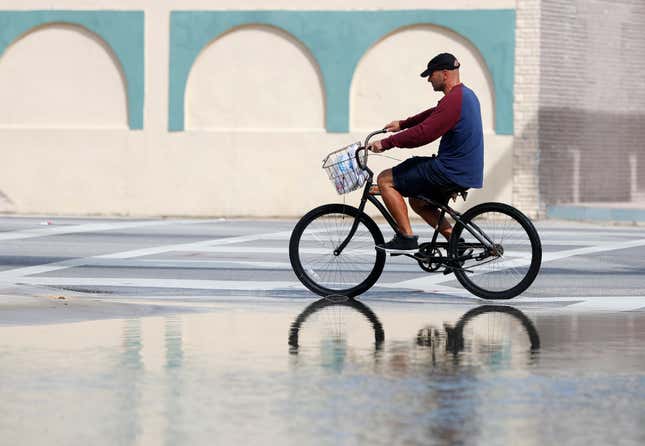 A cyclist rides past an area flooded during a King Tide, an especially high tide, Tuesday, Oct. 9, 2018, in Miami.