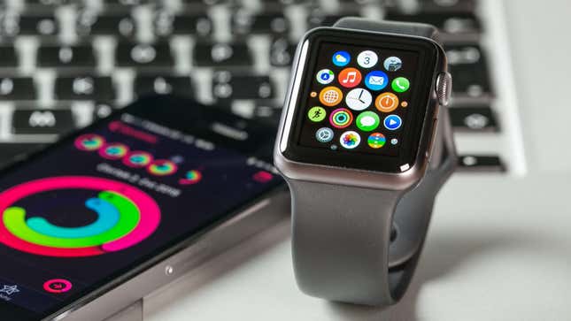 apple watch sitting on a desk next to an iphone and a computer