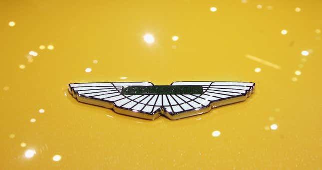 Old Aston Martin badge on the hood of a yellow car