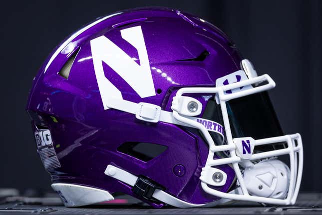 A shiny purple Northwestern football helmet, featuring a large white "N" and white facemask, sits before a black background.