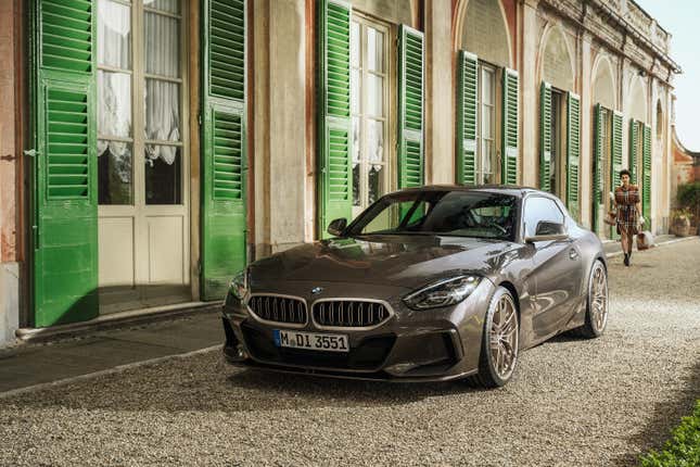 Un automóvil de concepto BMW Shooting Brake de color gris pardusco está estacionado frente a un edificio con persianas verdes.  Vista frontal de tres cuartos.