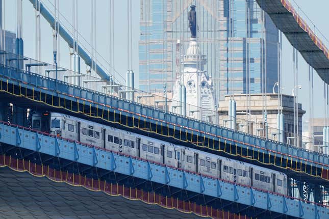 A Port Authority Transit Corporation (PATCO) train travels across the Benjamin Franklin Bridge in view of City Hall in Philadelphia, Friday, April 23, 2021.