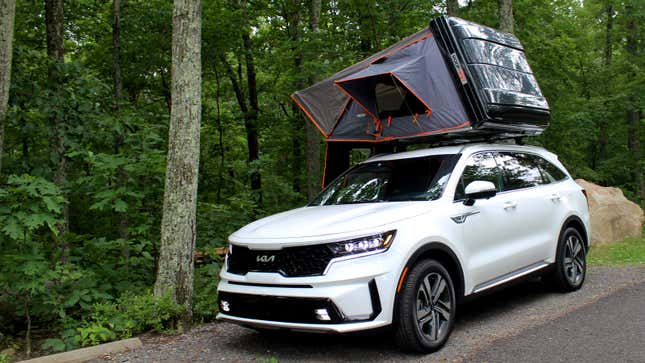 A photo of a white Kia Sorento PHEV SUV with a pop-up tent on the roof. 