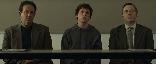 Jesse Eisenburg sits center between two lawyers from the movie The Social Network.