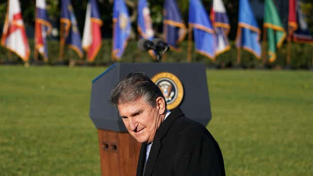 Sen. Joe Manchin walks in front of the presidential podium on the White House lawn.
