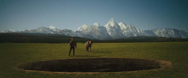 Royal Abbott (Josh Brolin) and his horse stand at the edge of a giant hole with a mountain range in the background.