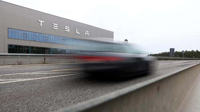 A photo of a car passing a Tesla plant. 