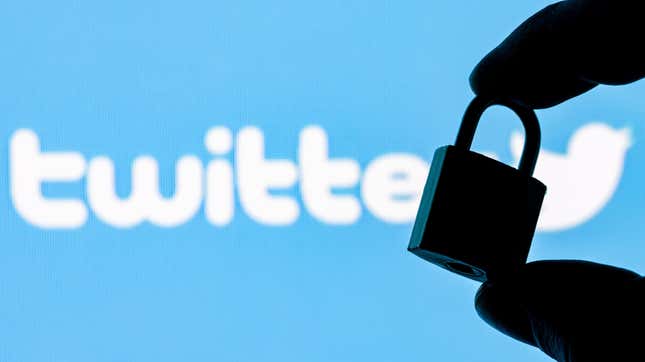 Fingers hold a closed security lock on the background of the Twitter social network logo.