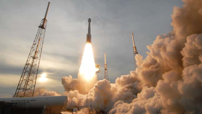 A photo of an Atlas V rocket launching in a cloud of smoke. 