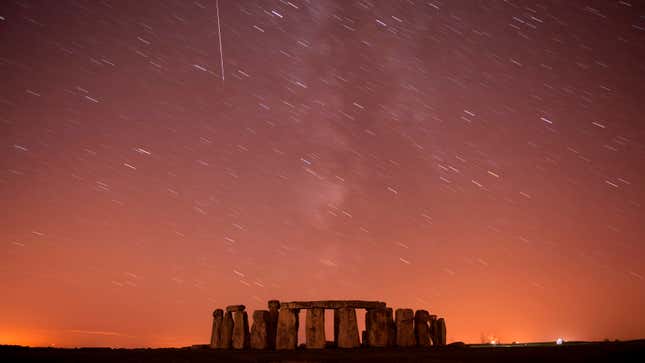 A meteor streaks past stars in the night sky over Stonehenge in Salisbury Plain, southern England.