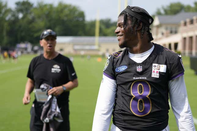 Jul 27, 2023; Owings Mills, MD, USA; Baltimore Ravens quarterback Lamar Jackson (8) smiles at a fan with Baltimore Ravens offensive coordinator Todd Monken standing in the background following training camp practice at Under Armour Performance Center.