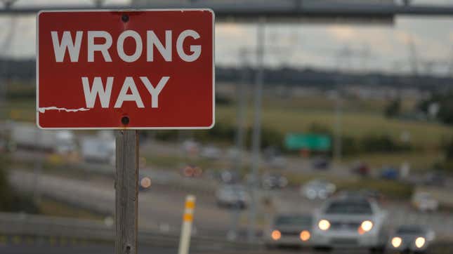 A red wrong-way sign posted alongside a highway