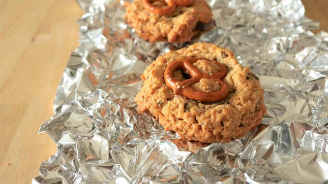 Two cookies sit on a wrinkly sheet of foil.