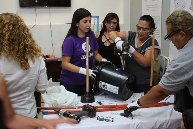 Women learn how to make a DIY washing machine with plastic buckets.