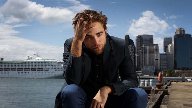 Robert Pattinson sits on a dock in Sydney Australia on a sunny day.