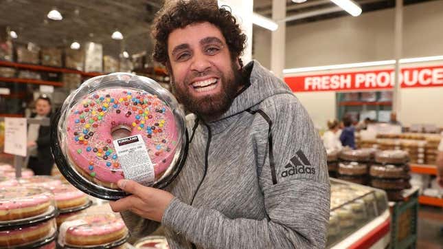 Man holding giant Costco doughnut in bakery section