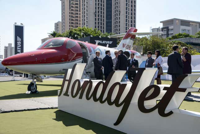 Attendees talk in front of the Honda Motor Co. HondaJet HA-420 exhibit during the Latin American Business Aviation Conference and Exhibition (LABACE) in Sao Paulo, Brazil, on Tuesday, Aug. 11, 2015. Billionaires will have their pick of business jets as Embraer and Cessna roll out shiny new models in a bid to woo buyers to a market that’s struggling to recover from the 2008 slump. 