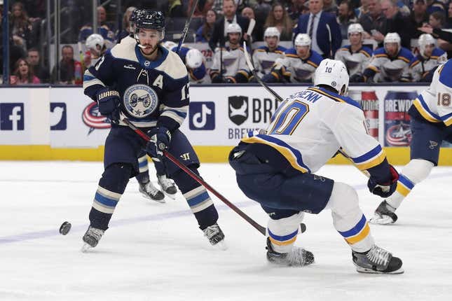 Mar 11, 2023; Columbus, Ohio, USA; St. Louis Blues center Brayden Schenn (10) sticks the puck away from Columbus Blue Jackets left wing Johnny Gaudreau (13) during the first period at Nationwide Arena.