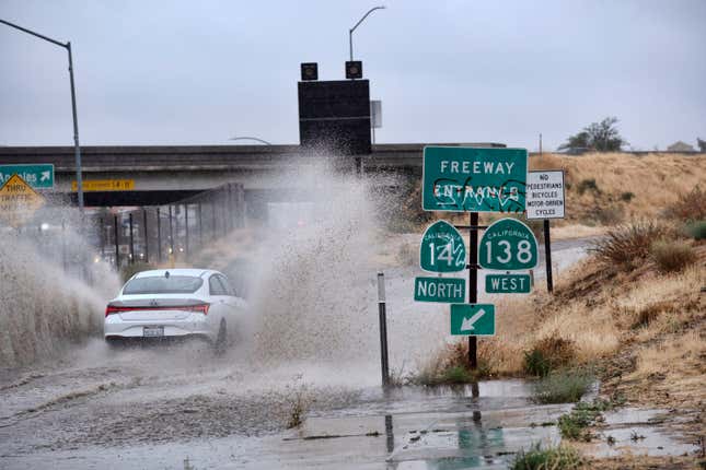 A vehicle drives through a flooded freeway entrance in Palmdale, California as a tropical storm moves into the area on Sunday, August. 20, 2023.