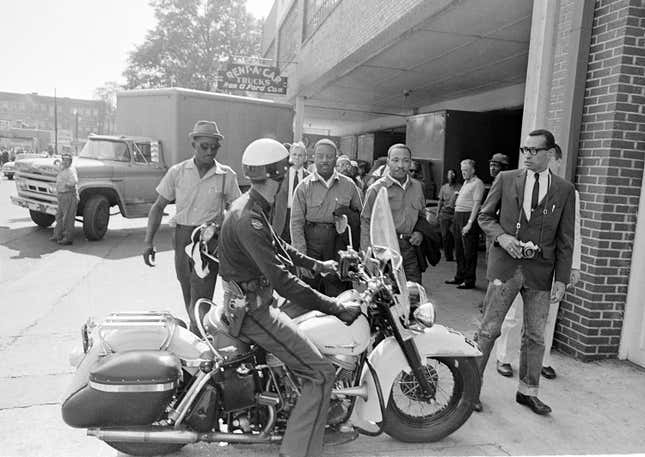 A police officer rolls his motorcycle in front of Birmingham demonstrators, including Rev. Ralph Abernathy, left, and Rev. Martin Luther King Jr., center.