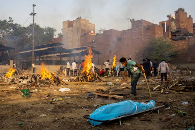 A man prepares a funeral pyre to cremate the body of a person, who died due to the coronavirus disease (COVID-19), at a crematorium ground in New Delhi