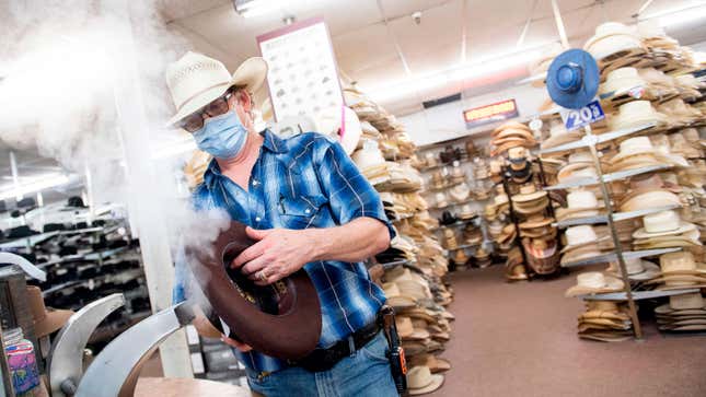A photo of a man steaming a cowboy hat. 