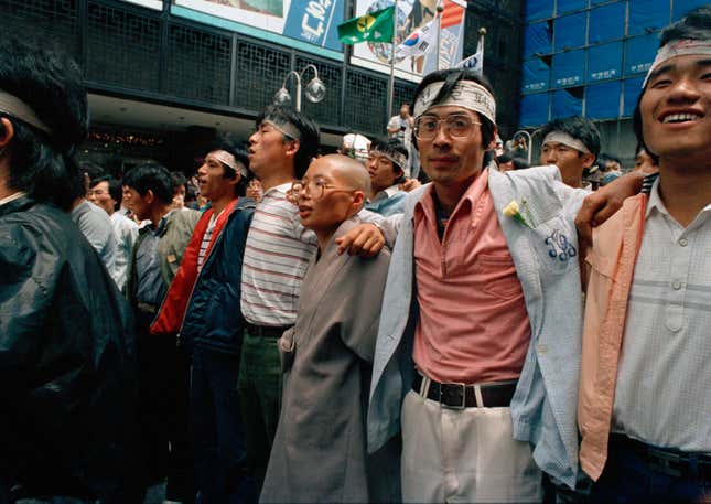 A Buddhist monk is flanked by protesters as they march in the street chanting anti-government slogans, in Seoul, South Korea, June 15, 1987.