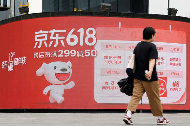 A resident, wearing a face mask following the coronavirus disease (COVID-19) outbreak, walks past a JD.com advertisement for the “618” shopping festival displayed outside a shopping mall in Beijing, China June 14, 2022. REUTERS/Carlos Garcia Rawlins