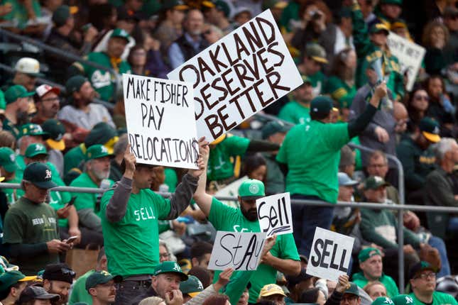 Fans hold signs inside of the Oakland Coliseum to protest the Oakland Athletics’ planned move to Las Vegas