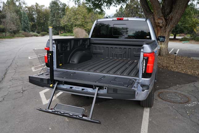 The bed of the 2023 Ford F-150 Lightning with bed step and hand hold extended.