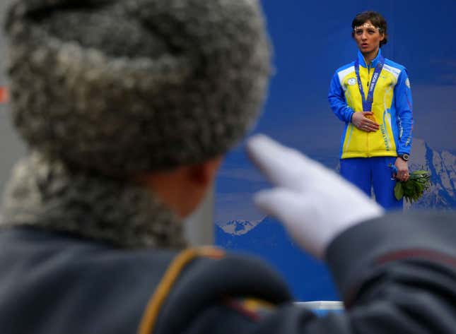 A Russian honor guard soldier salutes as Ukraine's Oleksandra Kononova covers her gold medal with her hand after winning the women's biathlon 12,5 km standing event during a medal ceremony at the 2014 Winter Paralympic, Saturday, March 15, 2014, in Krasnaya Polyana, Russia. The majority of Ukraine's Paralympic medalists covered their medals during medal ceremonies. (AP Photo/Dmitry Lovetsky)