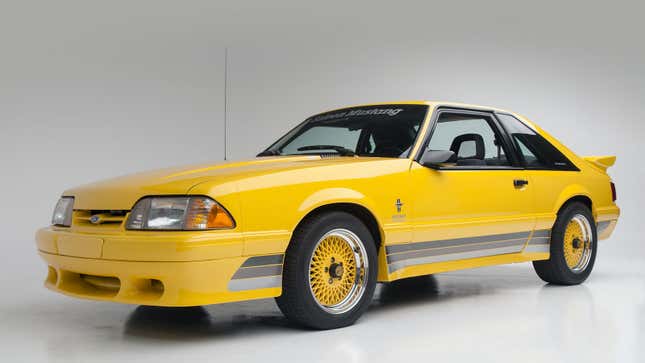 A photo of a bright yellow Saleen Mustang sports car in a studio. 