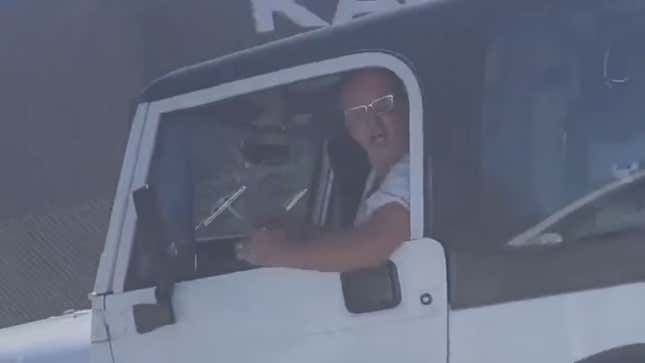A white man with a tiny mouth yells out of the window of his white Jeep Wrangler.