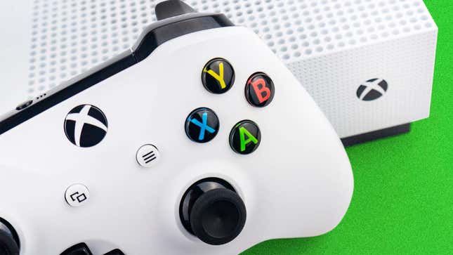 A close-up photo shows a white controller sitting on a white Xbox console. 